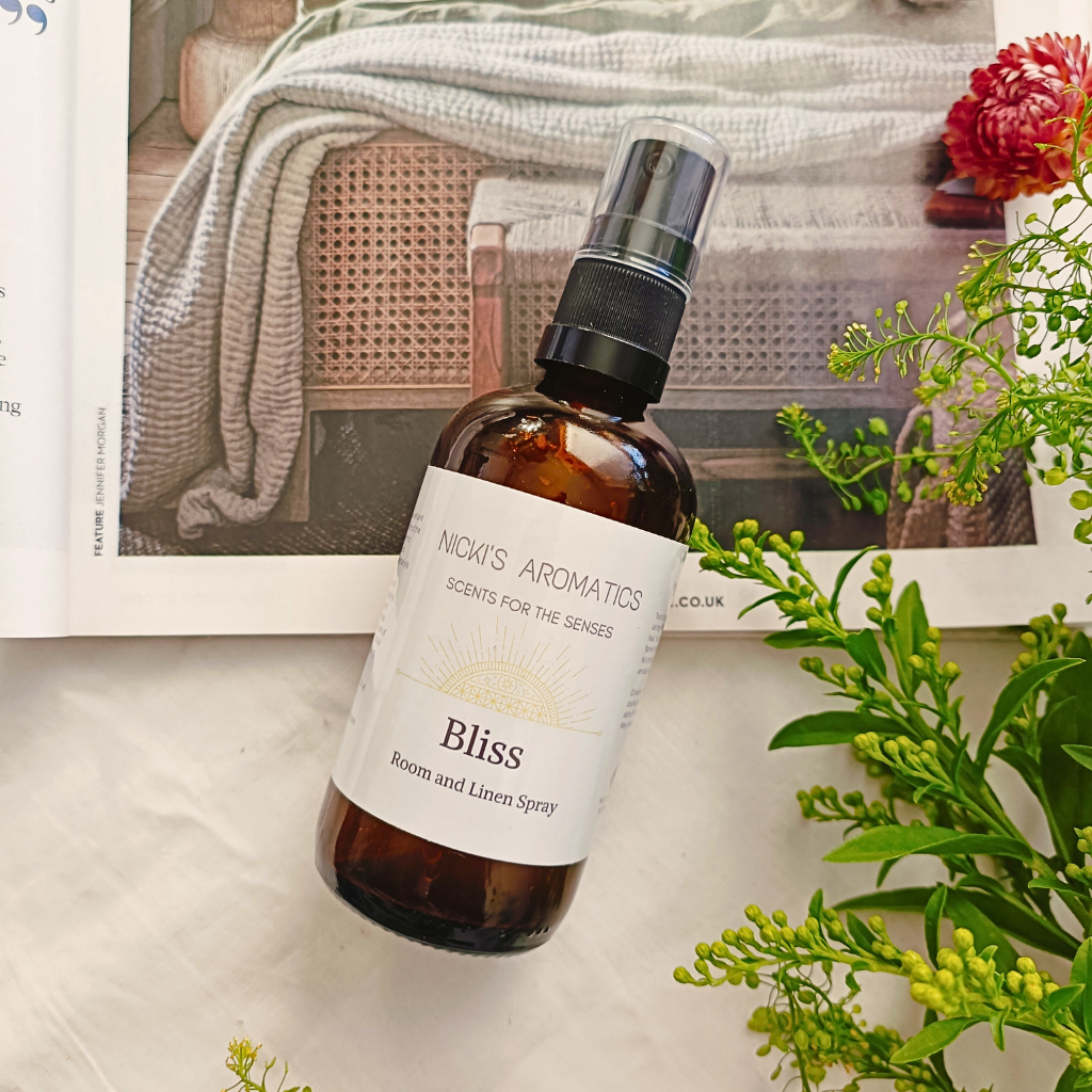 Bliss room and linen spray in a 100ml amber glass bottle resting on an open magazine