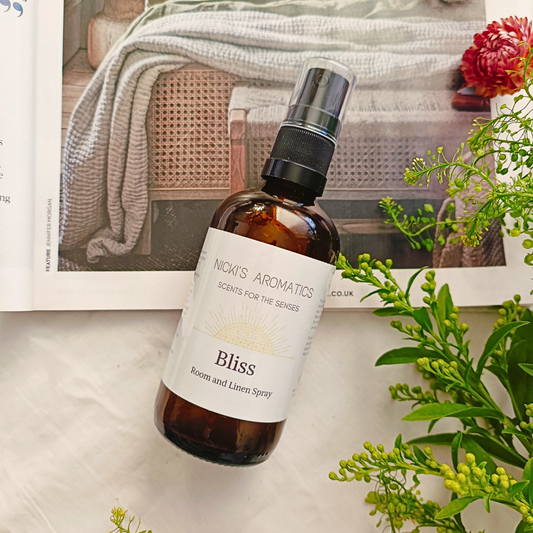 Bliss room and linen spray in a 100ml amber glass bottle resting on an open magazine
