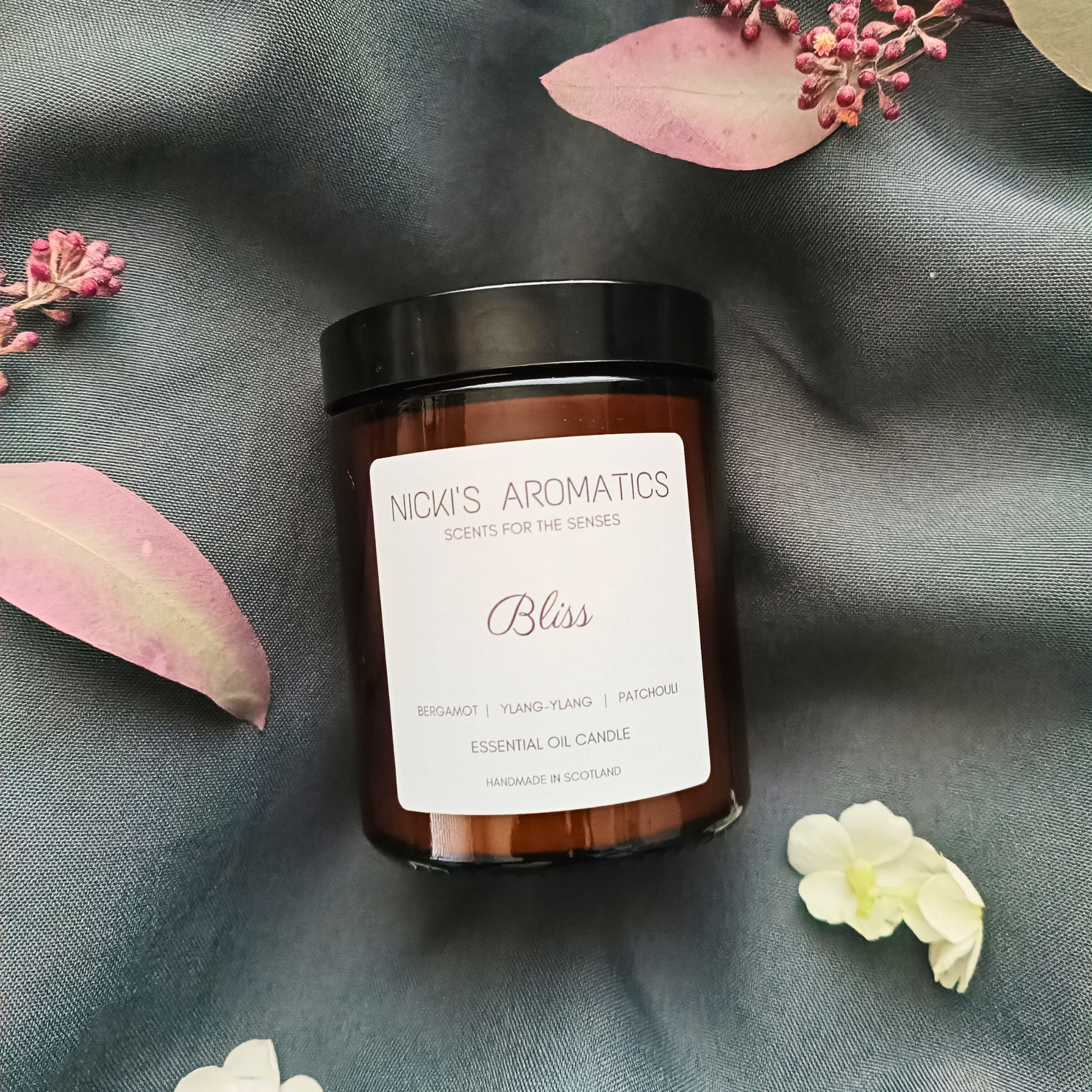 Bliss essential oil candle resting on a grey sheet