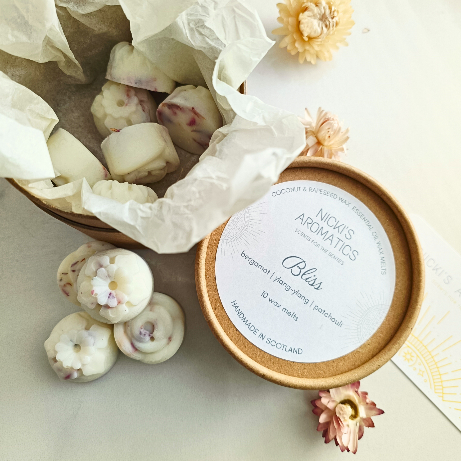 An open tube of Bliss essential oil wax melts in flower shapes