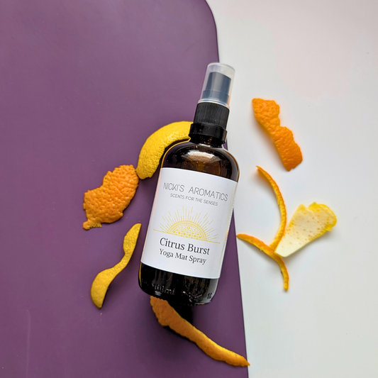 100ml amber glass bottle of Citrus Burst yoga mat spray surrounded by orange and lemon peel