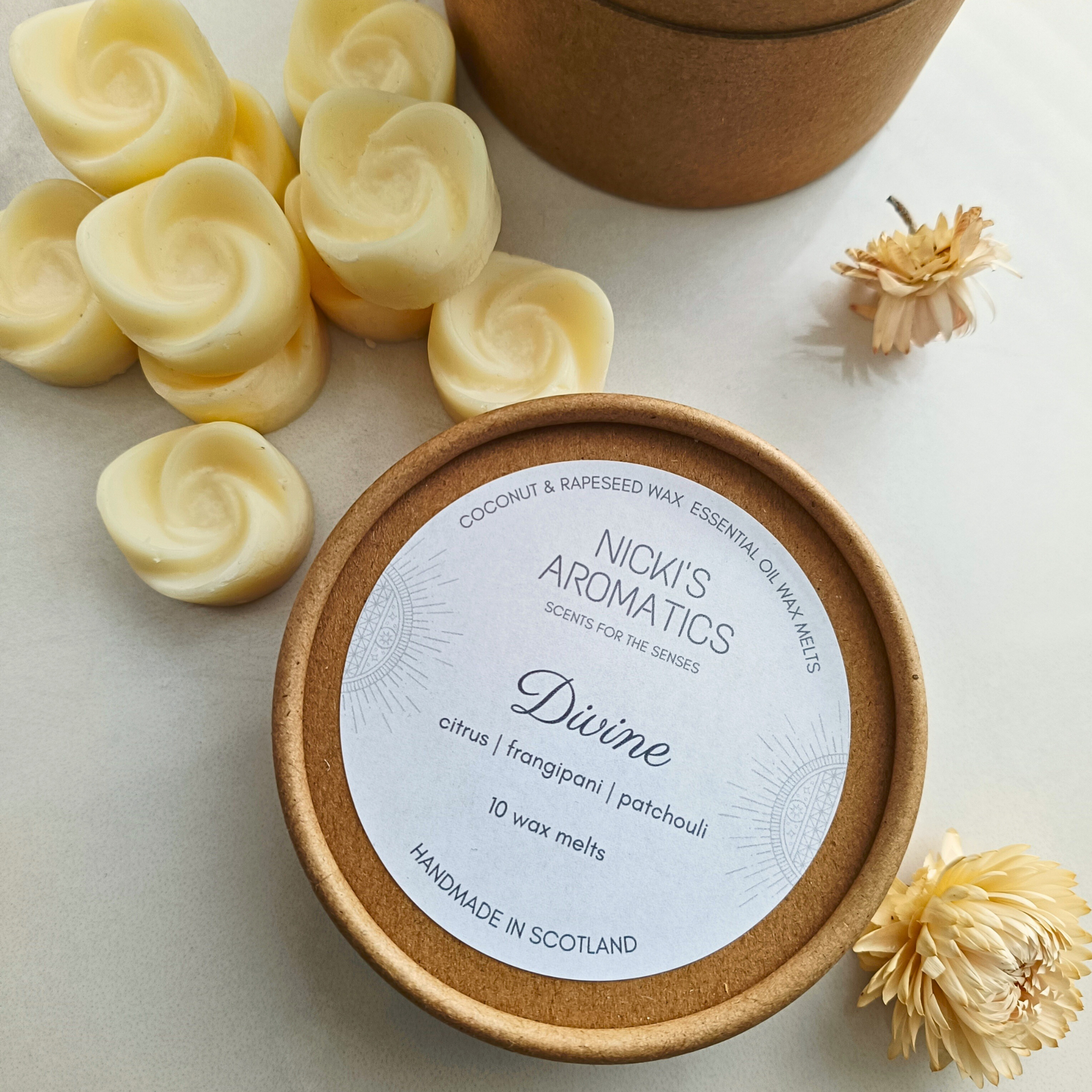 10 rose shaped Divine essential oil wax melts next to a kraft tub