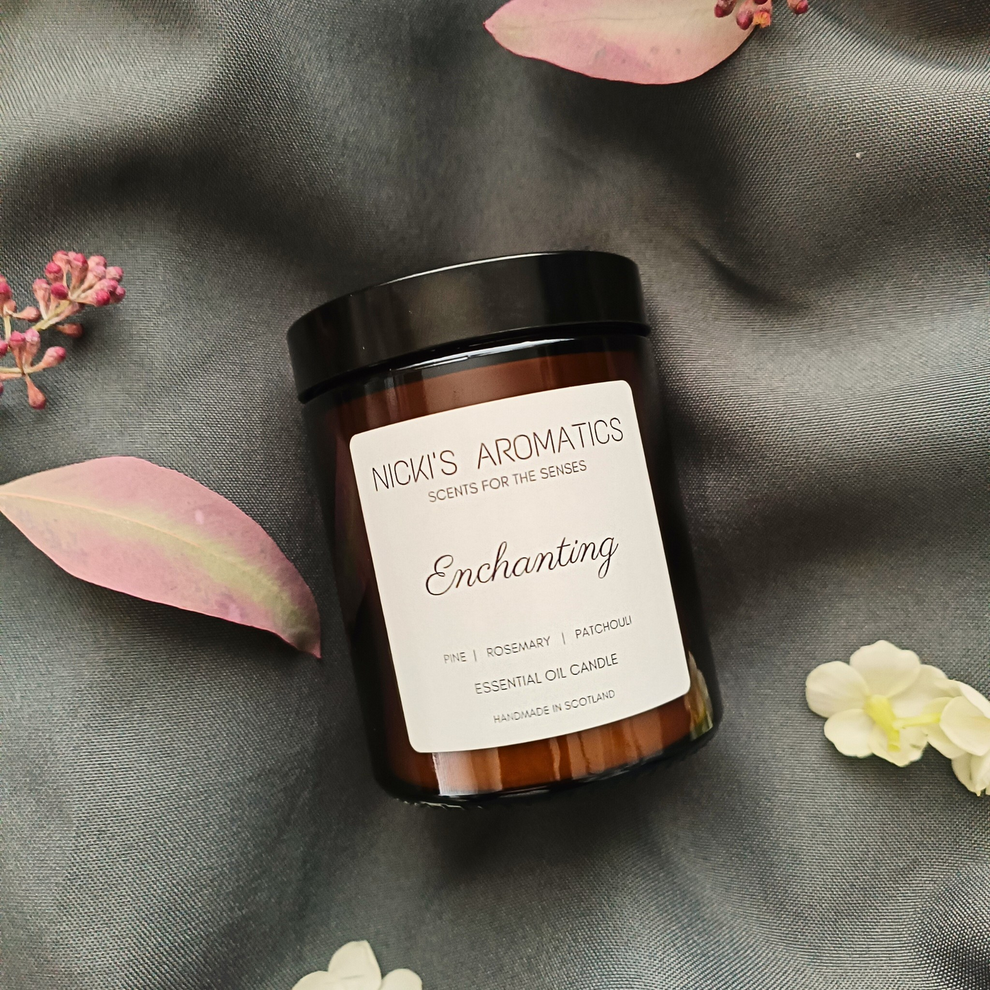 Enchanting essential oil candle in an amber glass jar resting o a grey sheet