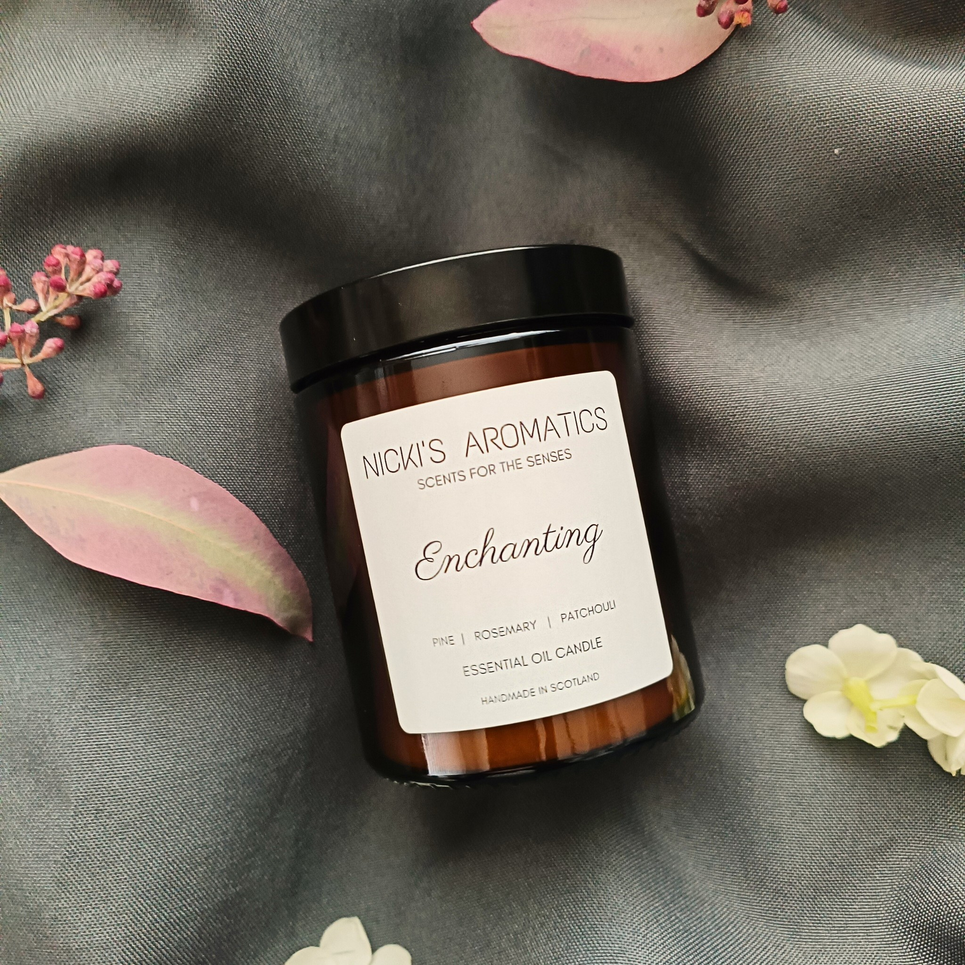 Enchanting essential oil candle in an amber glass jar resting o a grey sheet