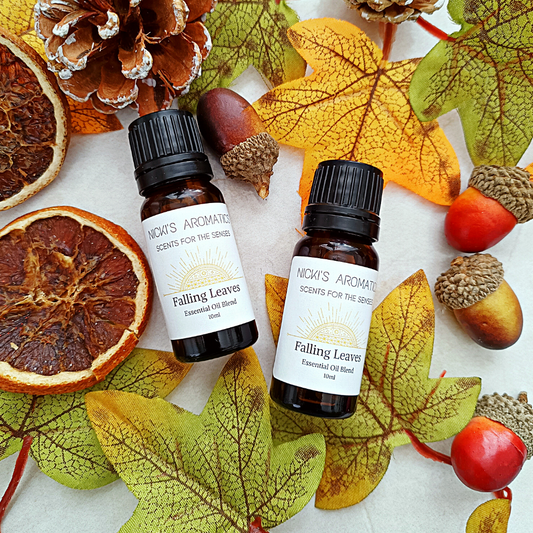 two 10ml amber glass bottles of Falling Leaves essential oil blend surrounded by autumn leaves, dried orange and acorns