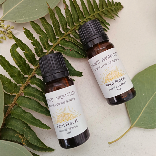 Two 10ml amber glass bottes of Fern Forest essential oil blend resting on a fern and some leaves