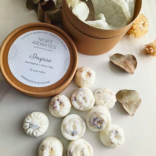 An open kraft tube with 10 Inspire essential oil wax melts next to it