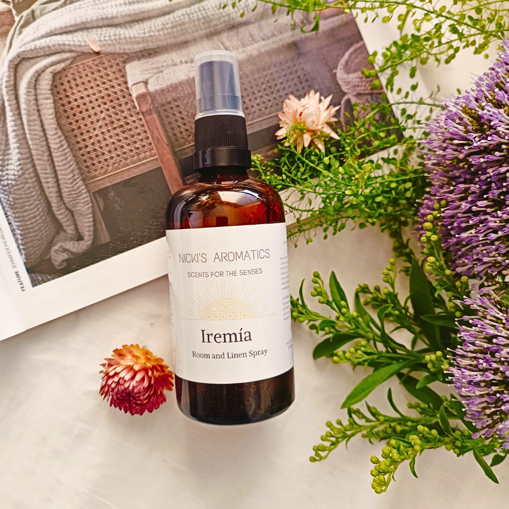 Iremia essential oil room and linen spray in an amber glass bottle resting on an open magazine