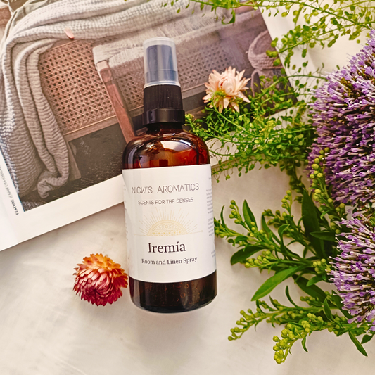 Iremia essential oil room and linen spray in an amber glass bottle resting on an open magazine