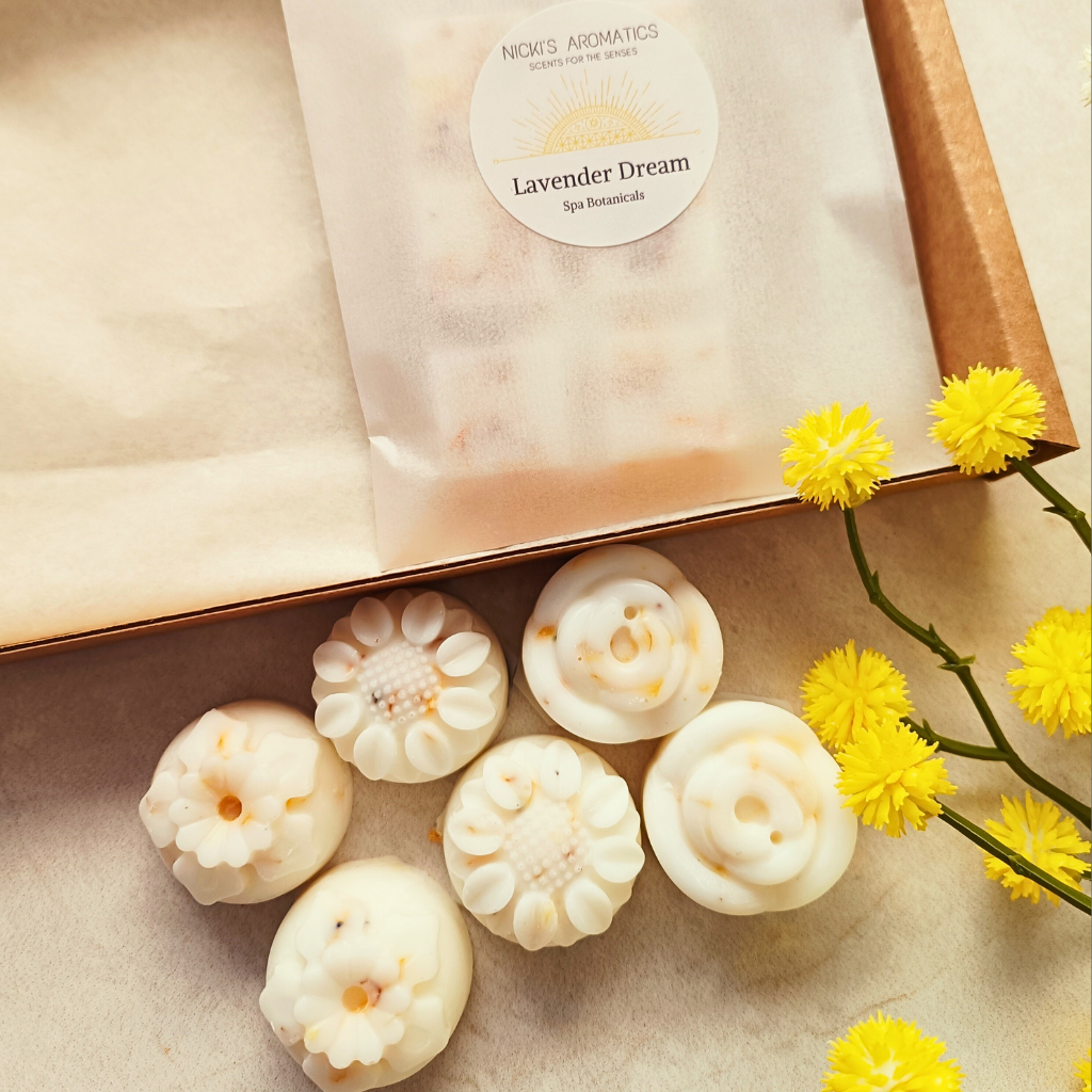 6 flower shaped Lavender Dream essential oil wax melts next to an open postal box with a Lavender Dream wax melt bar in it