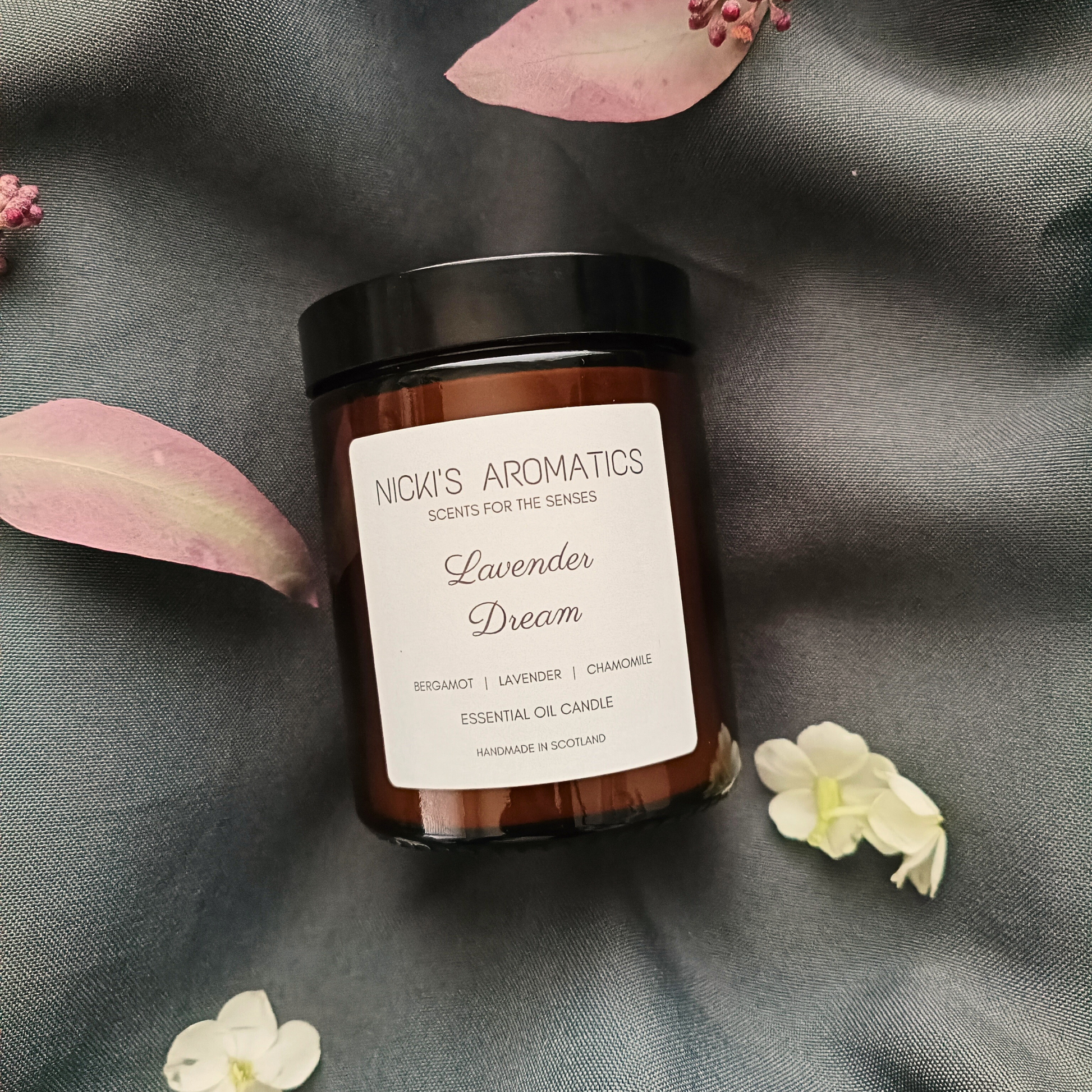 Lavender Dream essential oil candle in an amber glass jar on a grey sheet