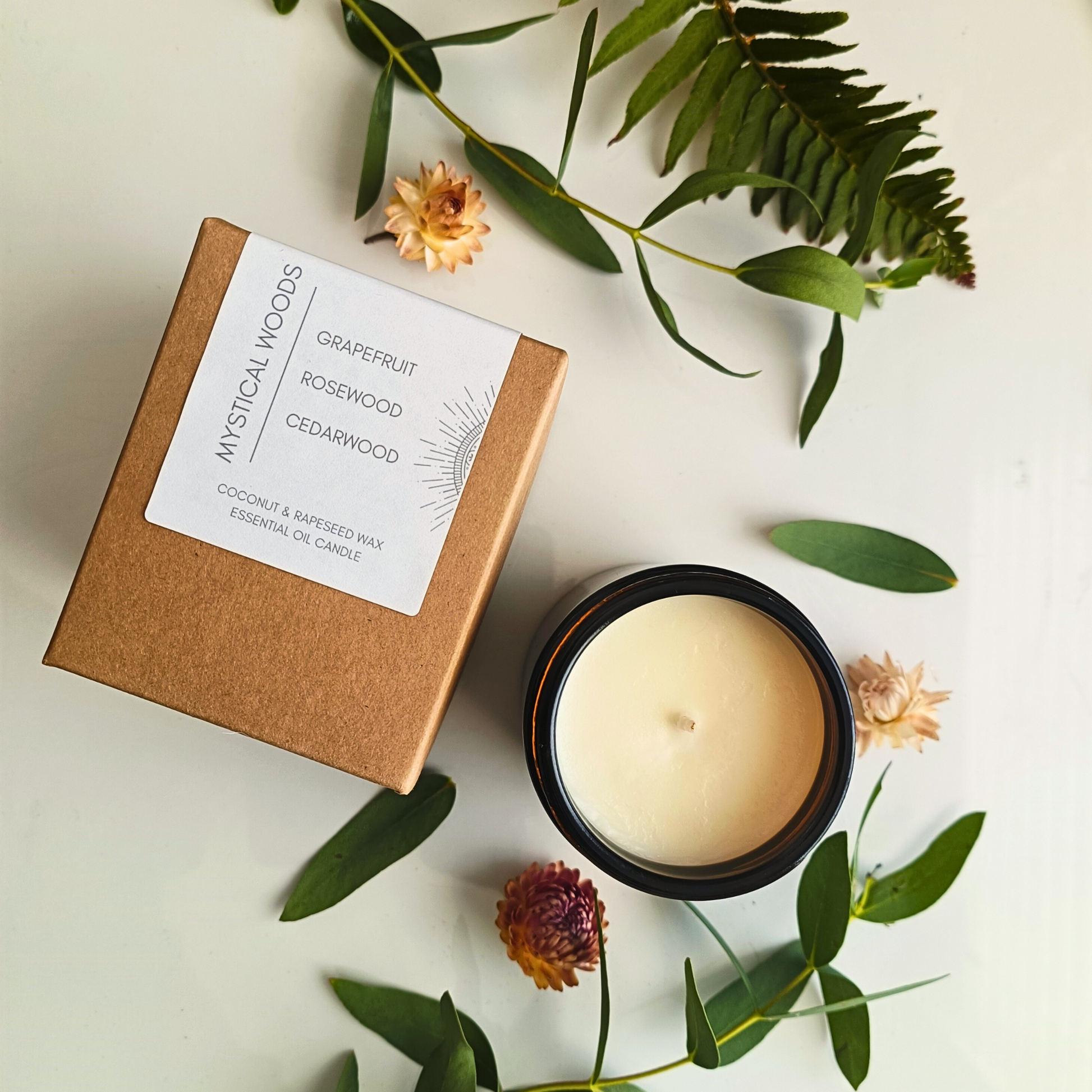 A kraft box labelled Mystical Wood candle next to an open candle