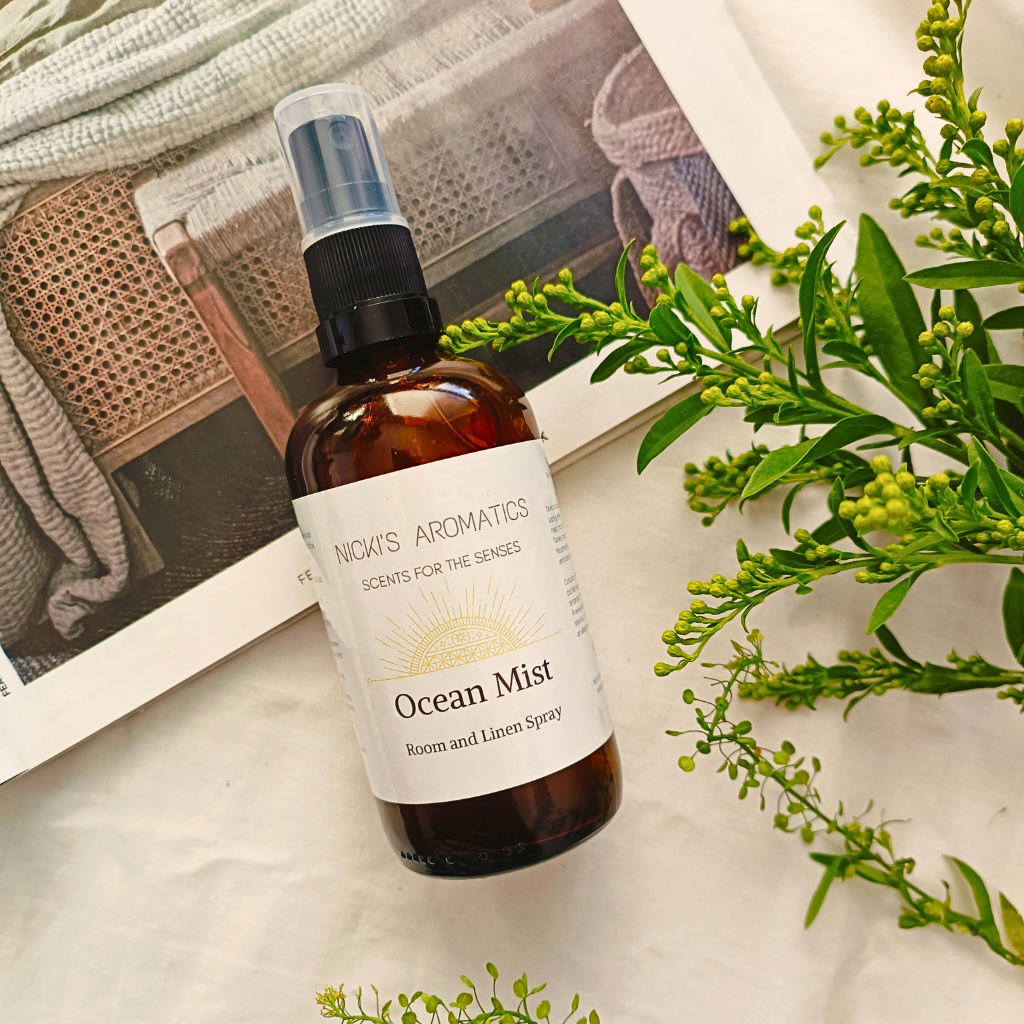 Ocean Mist essential oil room and linen spray in an amber glass bottle on a magazine