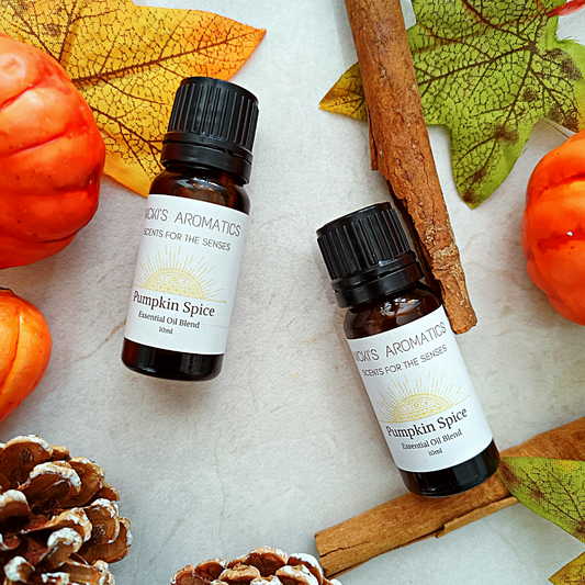 Two 10ml amber glass bottles of Pumpkin Spice essential oil blend surrounded by autumn leaves, cinnamon sticks and pumpkins