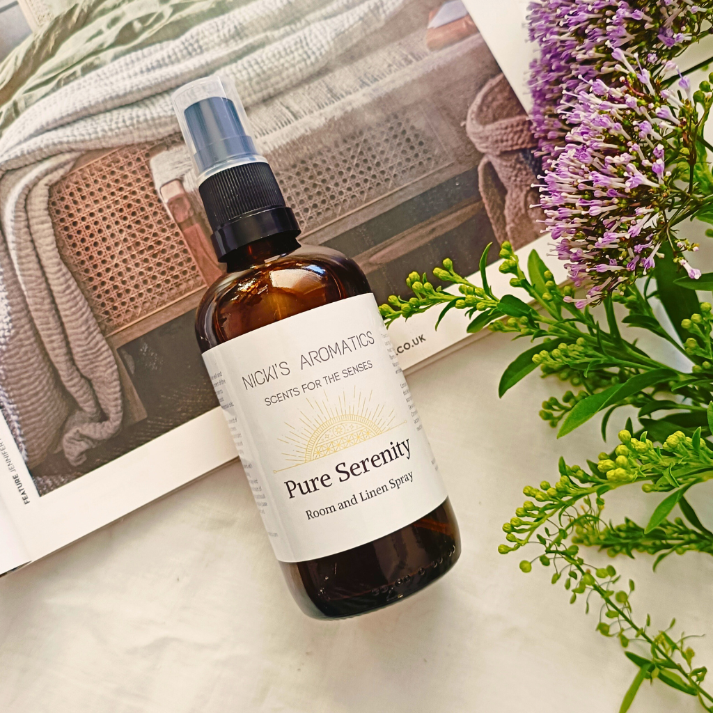 Pure Serenity natural room and linen spray in a 100ml amber glass bottle resting on an open magazine