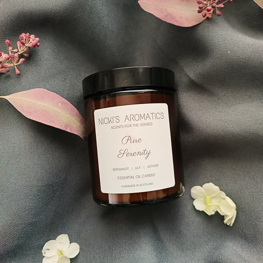 Pure Serenity essential oil candle in an amber glass jar resting on a grey sheet