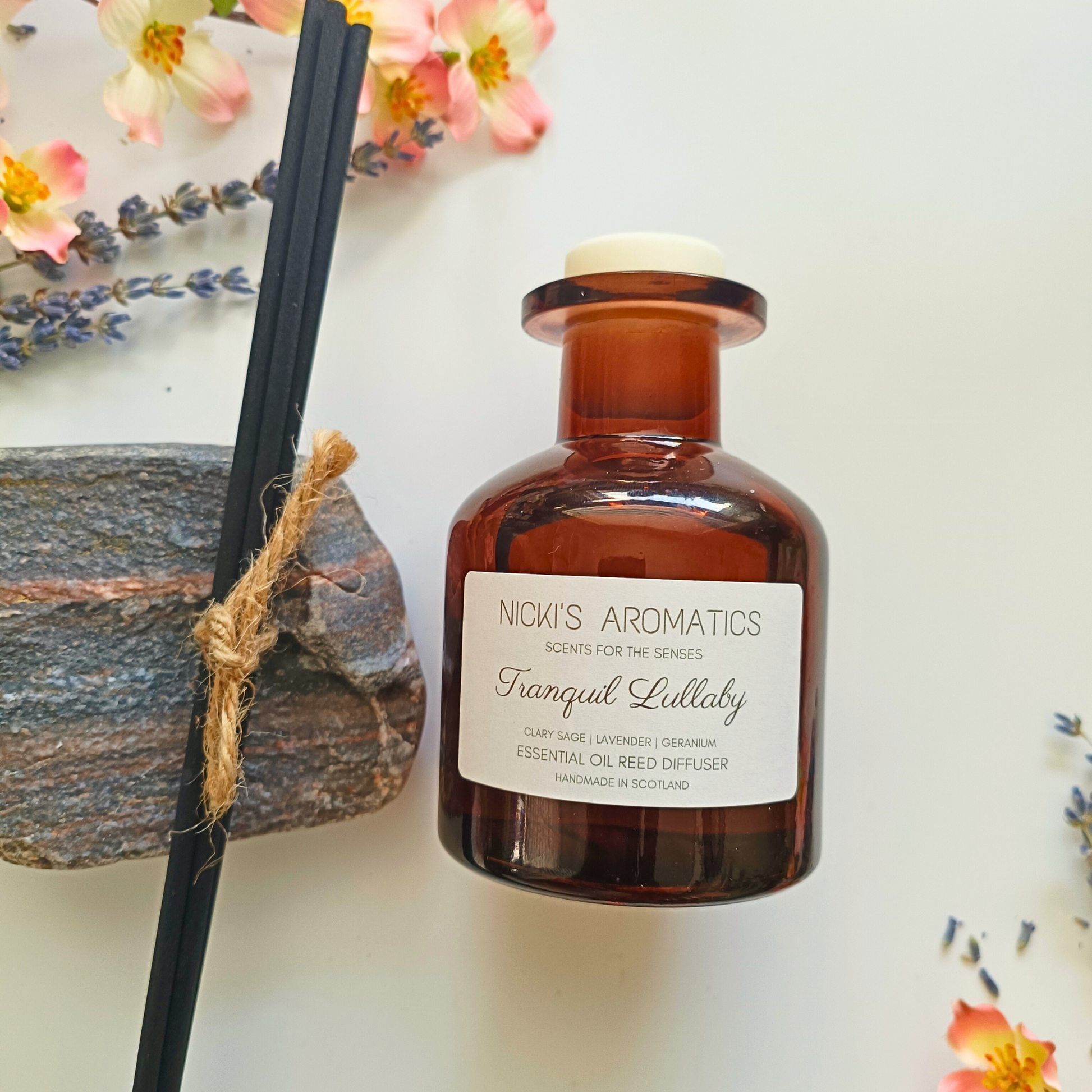 natural essential oil reed diffuser in an amber glass apothecary style bottle, with 4 black fibre reeds to the left
