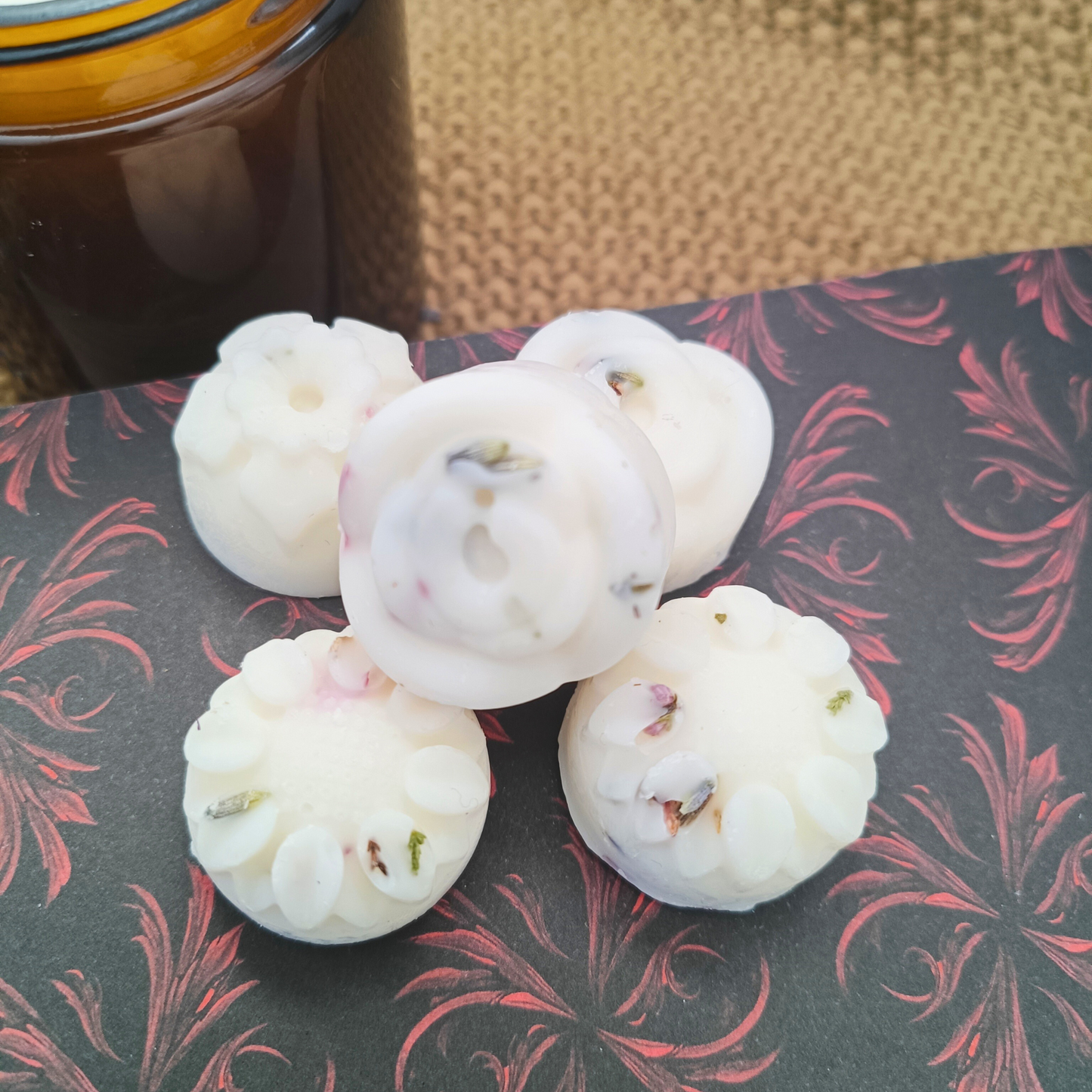 five flower-shaped wax melts containing botanicals, sat on an open book