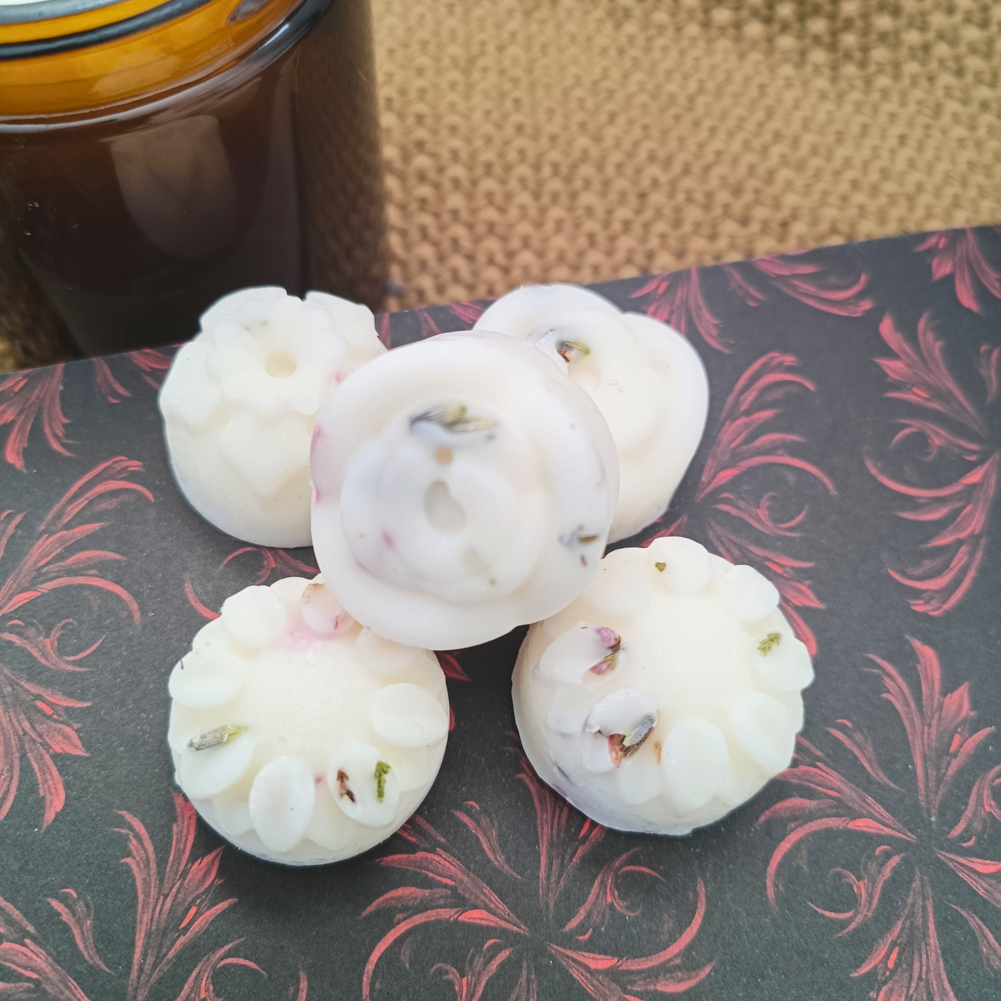 five flower-shaped wax melts containing botanicals, sat on an open book