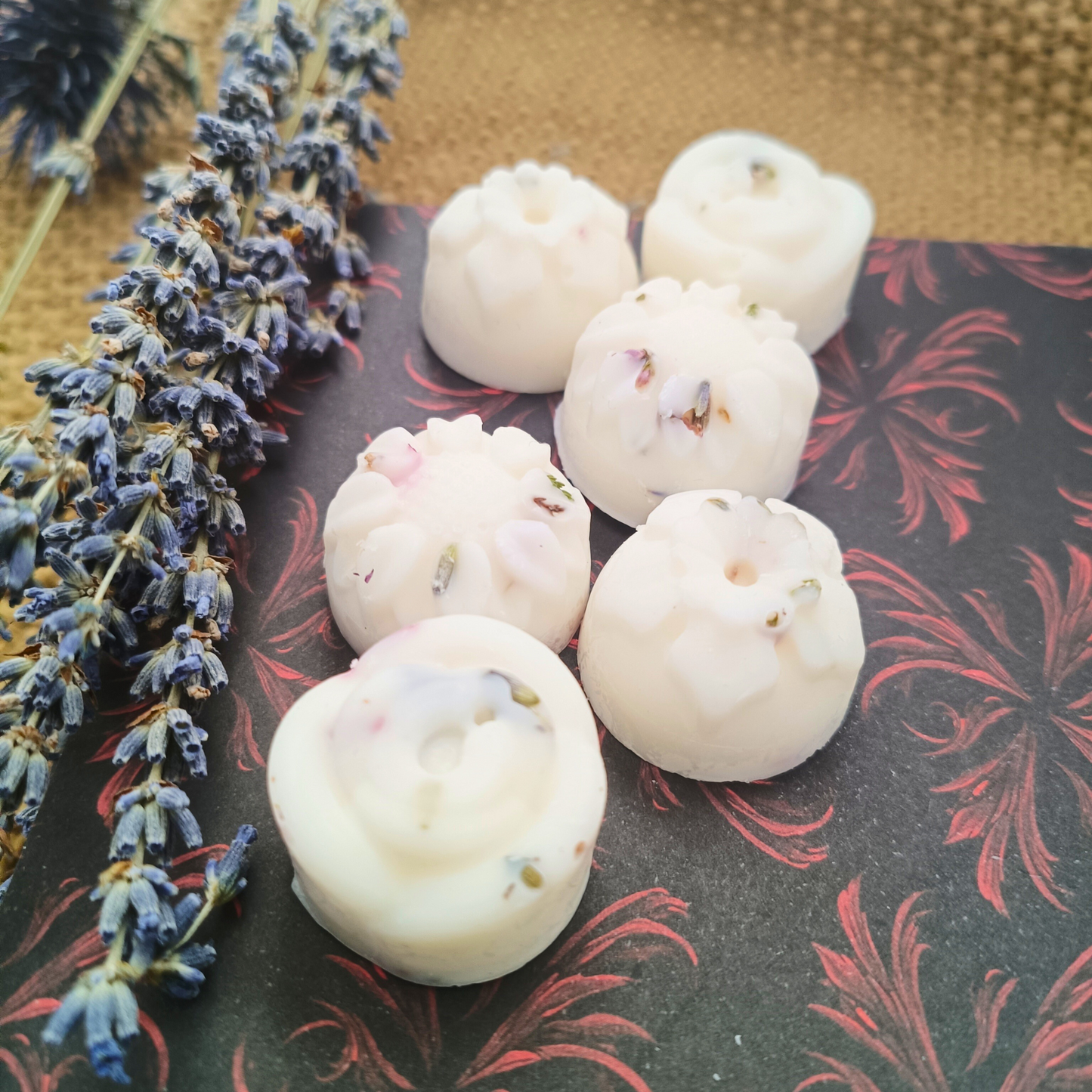 six flower-shaped botanical essential oil wax melts next to lavender stalks