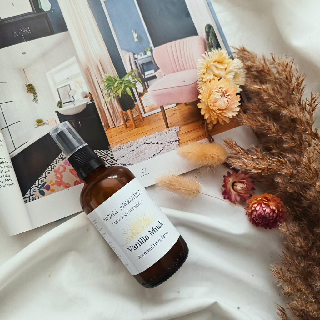 An amber glass bottle of Vanilla Musk essential oil room and linen spray on a magazine