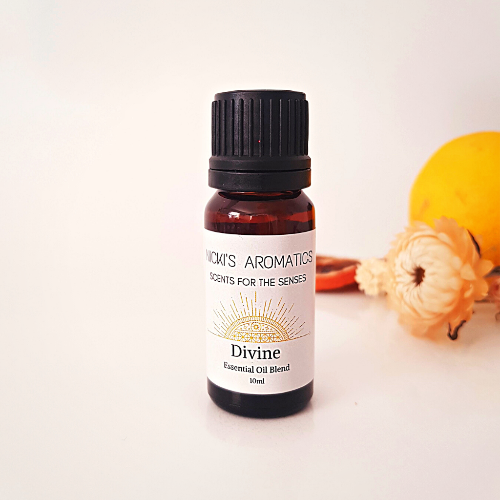 A 10ml amber glass bottle of Divine essential oil blend with a flower, dried orange and a fresh lemon