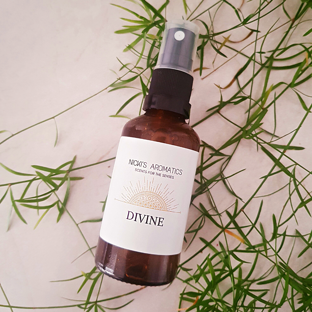 A 50ml amber glass bottle of Divine room and linen spray on small leaves