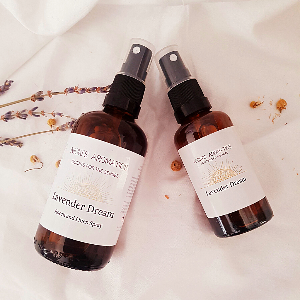 Lavender Dream room linen and pillow spray in 100ml and 50ml amber glass bottles resting on a white sheet