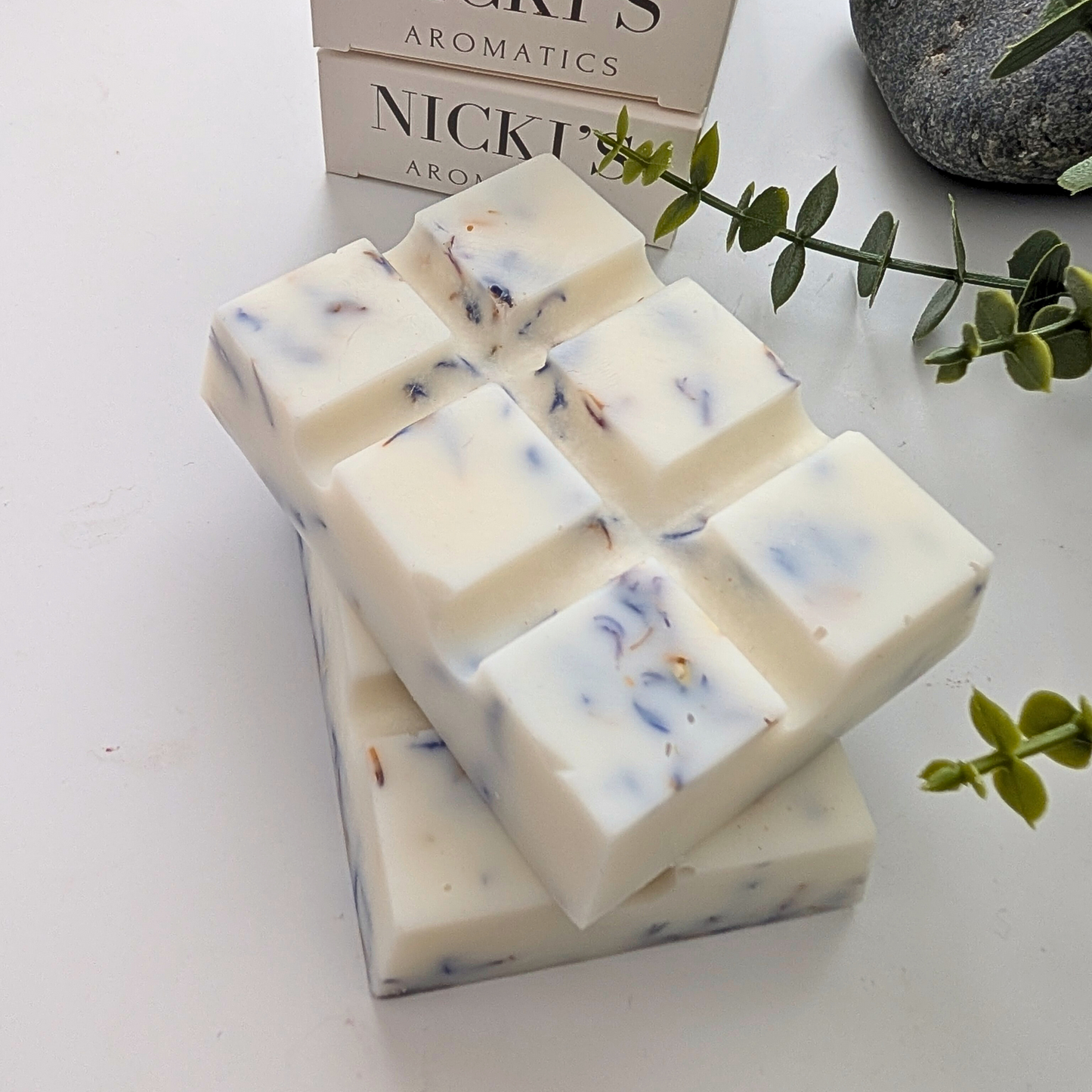 Pure Serenity chunky wax melt bars with botanicals in front of Nicki's Aromatics wax melt boxes