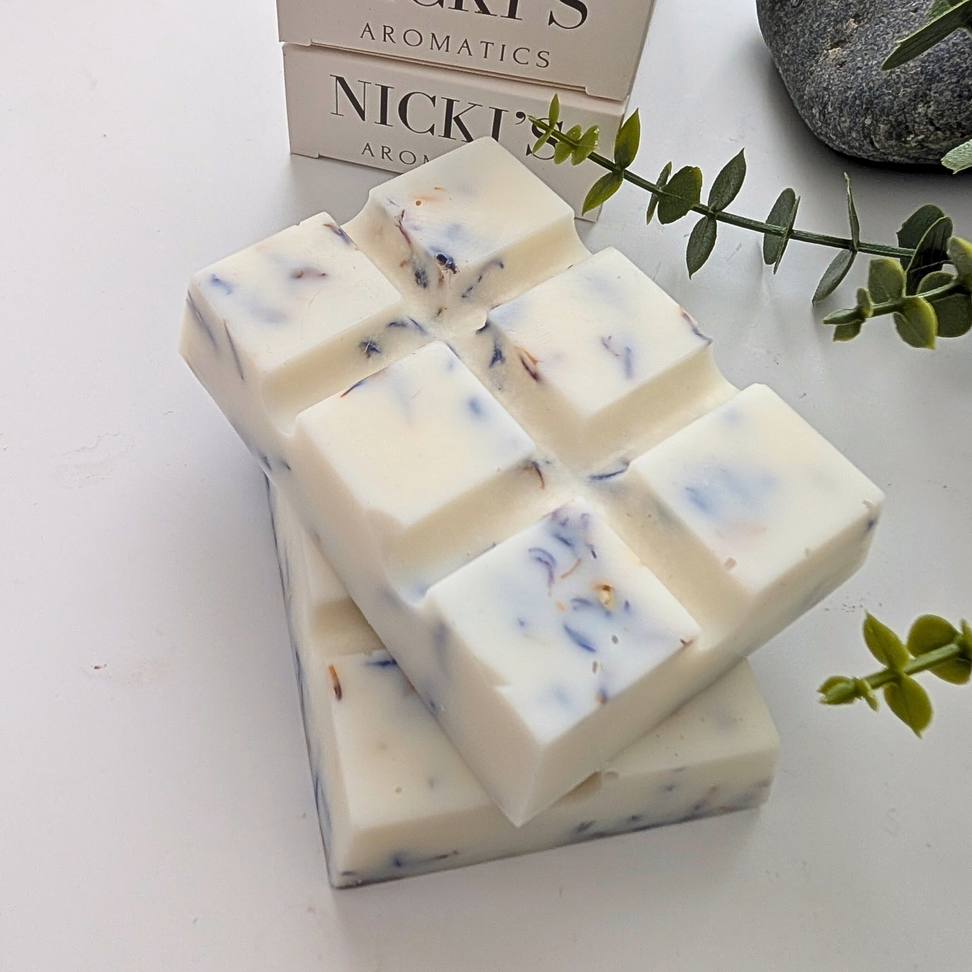 Pure Serenity chunky wax melt bars with botanicals in front of Nicki's Aromatics wax melt boxes